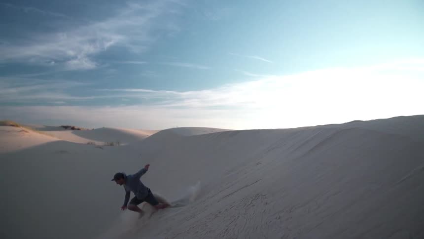 A man is jumping over a dune