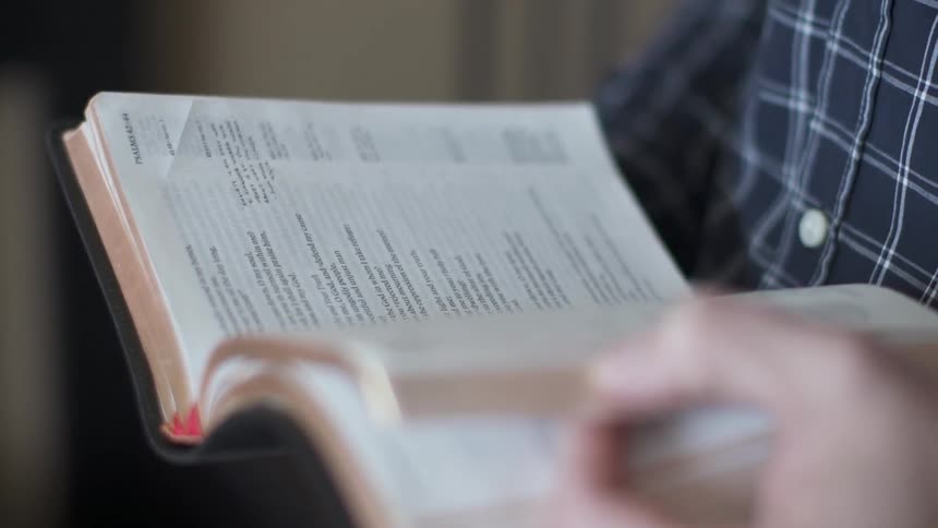 Man sitting in living room reads bible