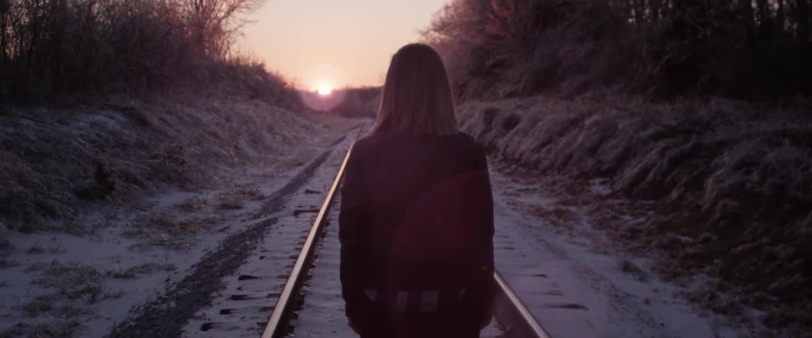 A person walking along the train tracks