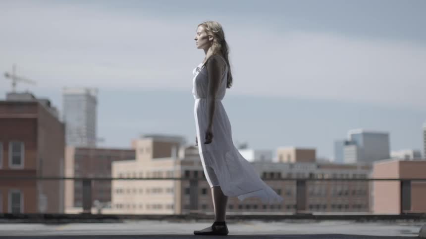 Woman standing on the rooftop of a building in a flowing dress