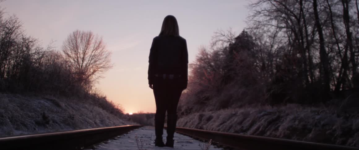 A person walking along the train tracks