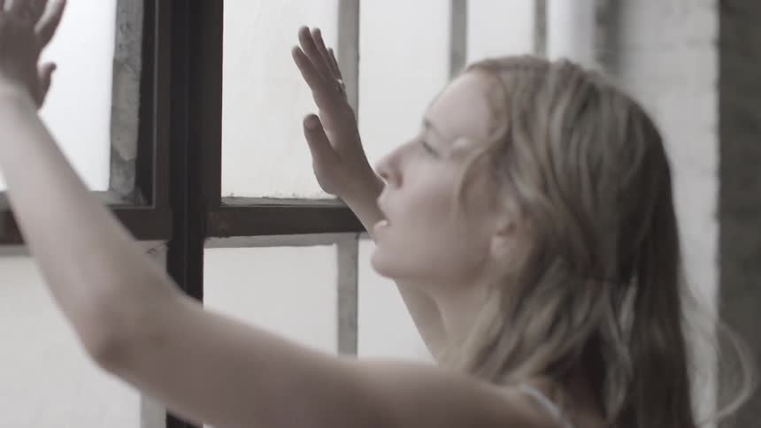 A woman looks through a paned window