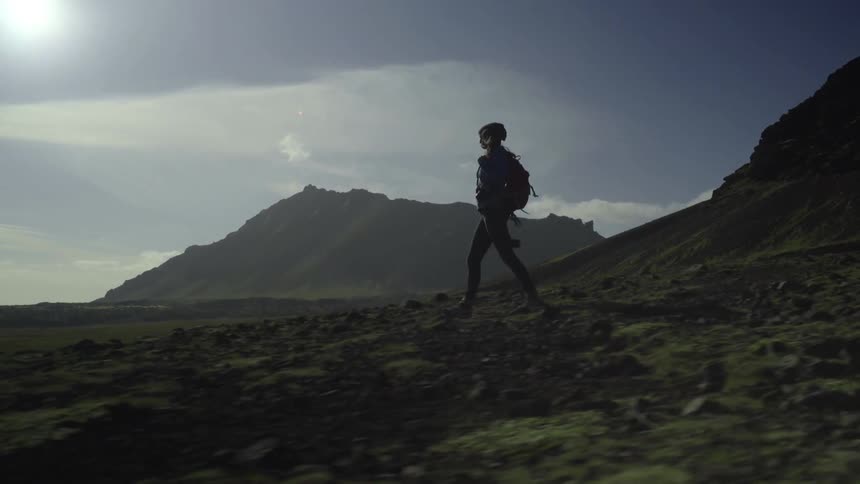 Woman walking downhill with mountains in the background