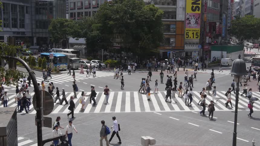 Crowds of people walk across a city street  Shibuya Tokyo