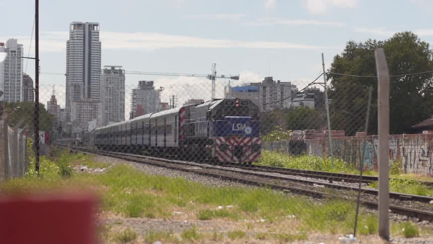 Train running beside a wire fence