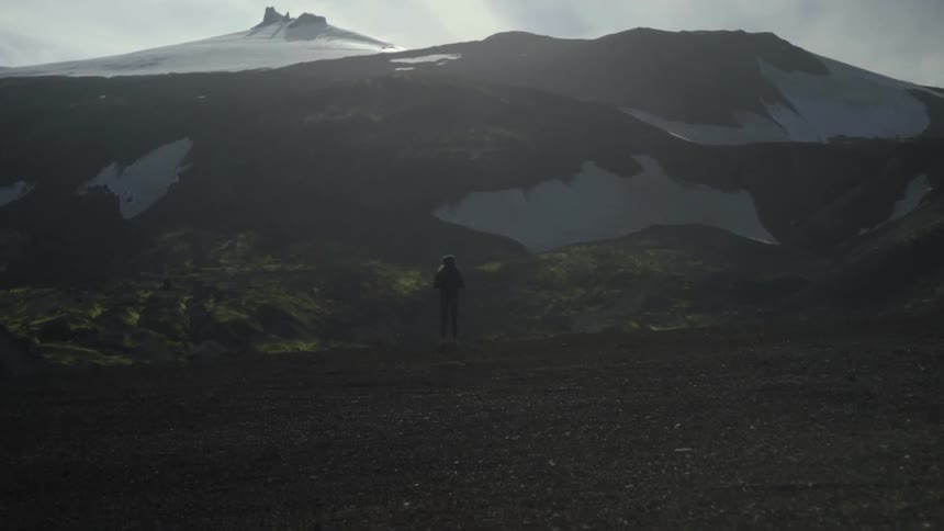 Person standing and looking out at a snowy mountain