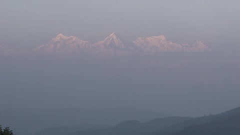 A view of snow-capped mountains rising above clouds