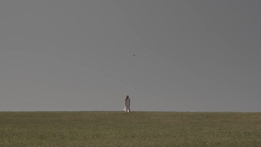 A woman in a white dress walking in a field