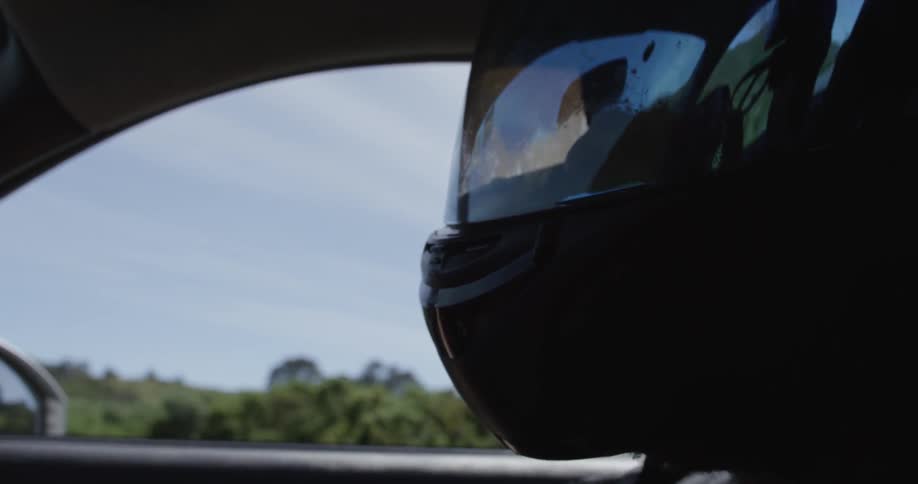 A person wears a helmet, while inside a vehicle