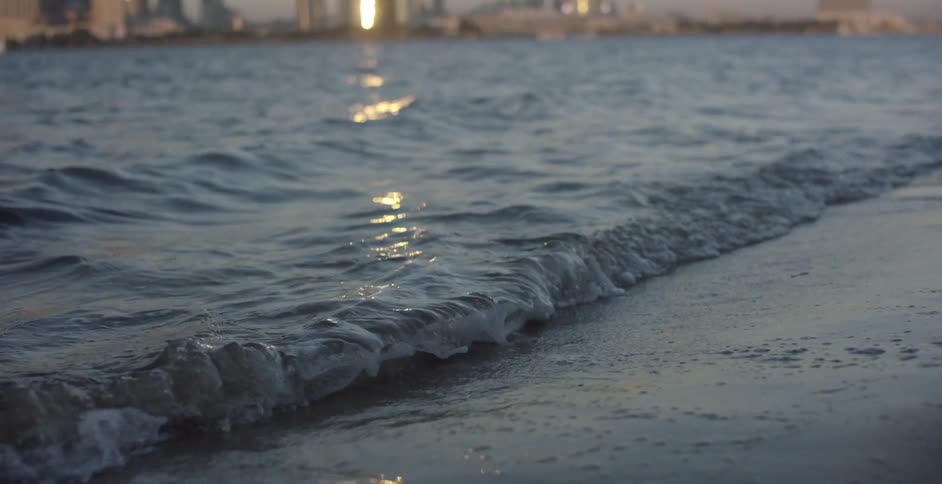Waves wash onto a beach in front of a city