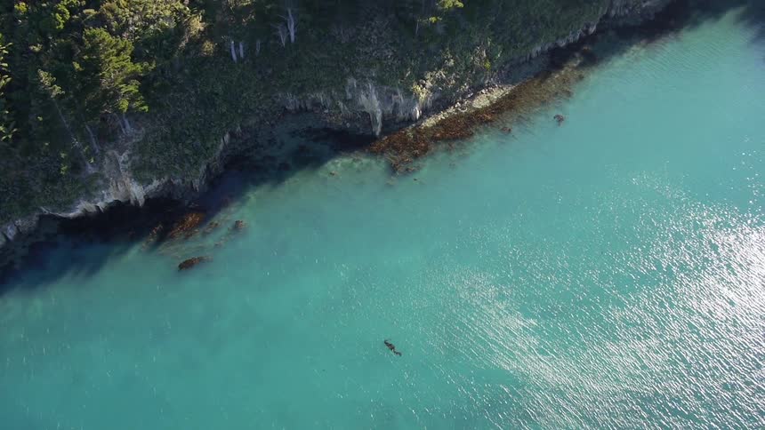 Aerial view of blue ocean water near a rocky cliff
