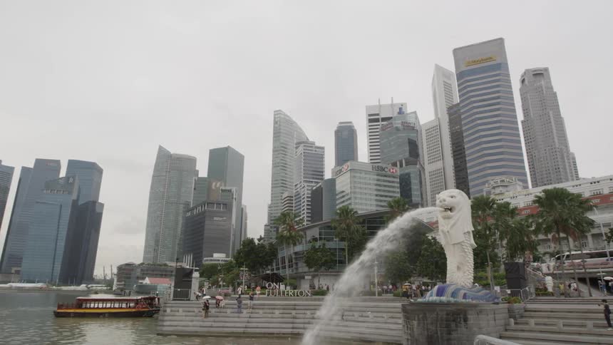 Landscape view of a city skyline and waterfront with a statue shooting water out of the mouth in the foreground