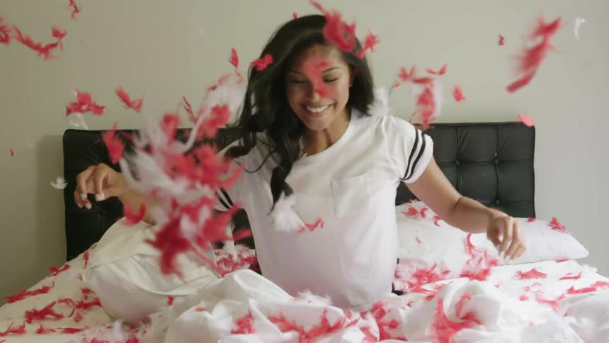 A person throwing feathers on a bed