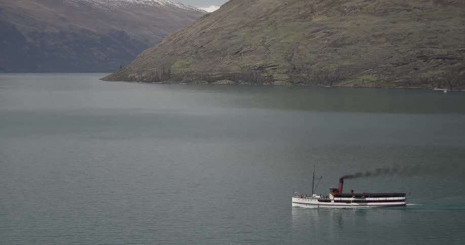 Large boat floating down a river surrounded by mountains
