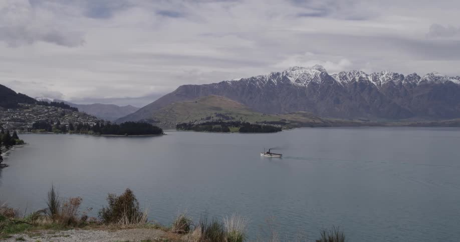 A small boat on a lake that is surrounded by snow capped mountains