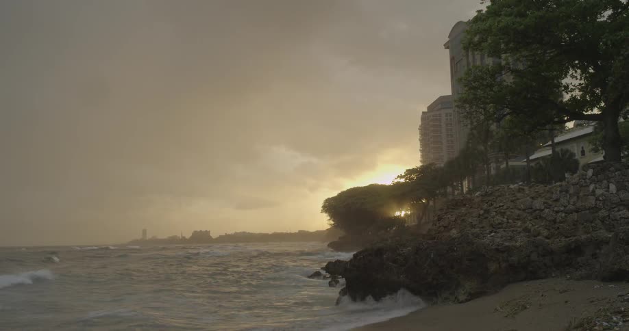 Waves crash onto a beach at sunset