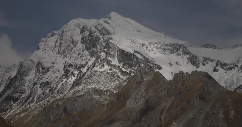 A majestic, snow capped mountain on a partly cloudy day