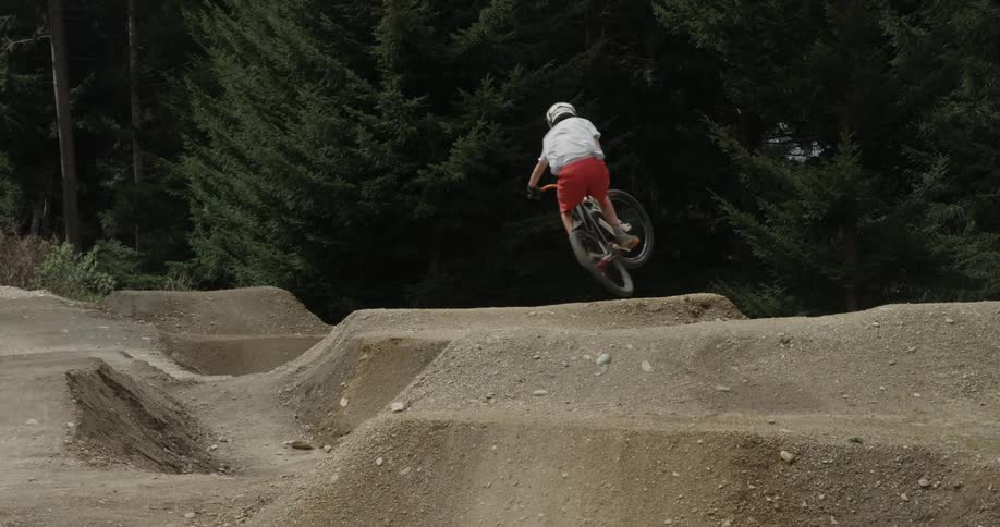 A bicyclist jumps over a dirt ramp
