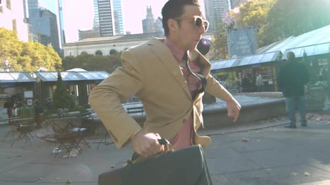 A man in a suit runs through an urban area with his briefcase