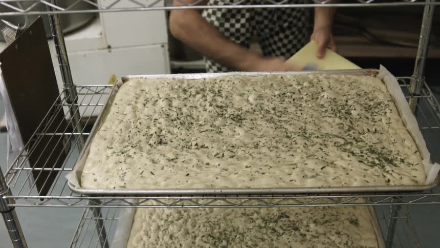 A person seasoning some raw dough