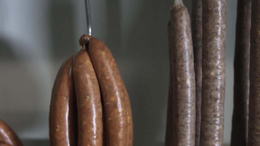 Sausages hang from hooks