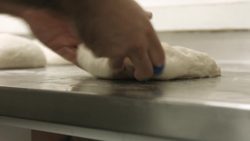 A man kneading and shaping dough