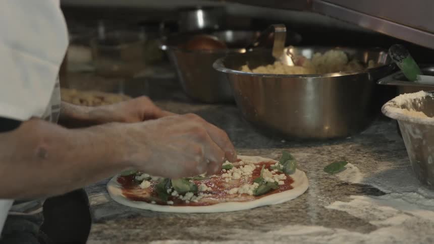 Person quickly making several pizzas at the same time