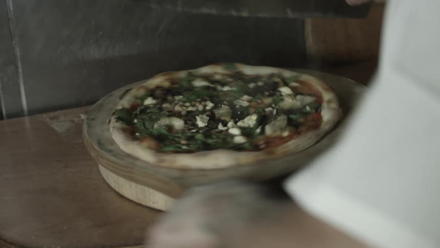 A chef cutting and plating a pizza