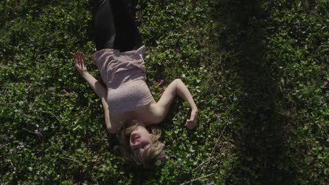 Smiling woman rolling over and laying in the green grass
