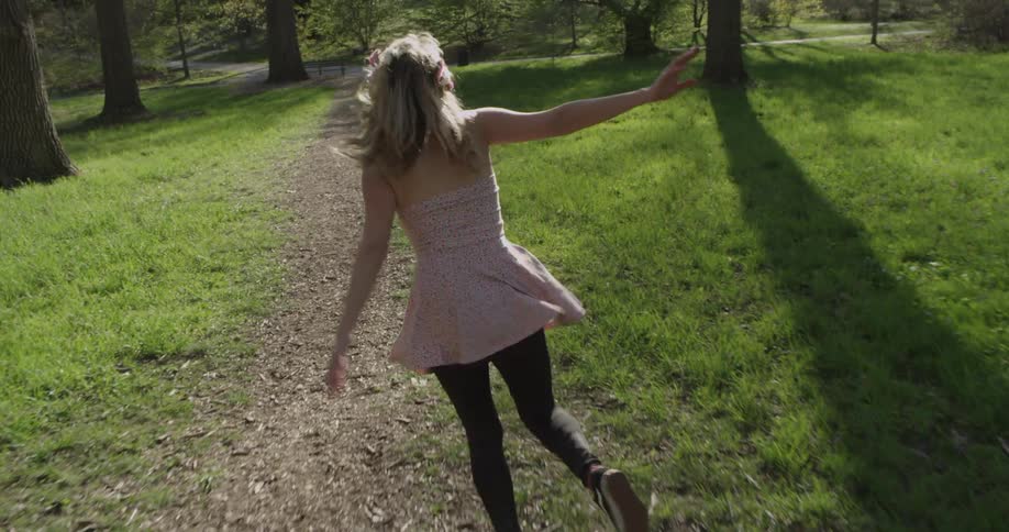 A young girl playfully runs down a path