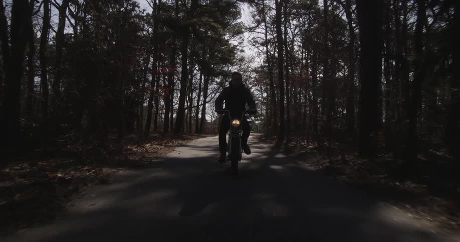 A motorcyclist bikes down a forest road