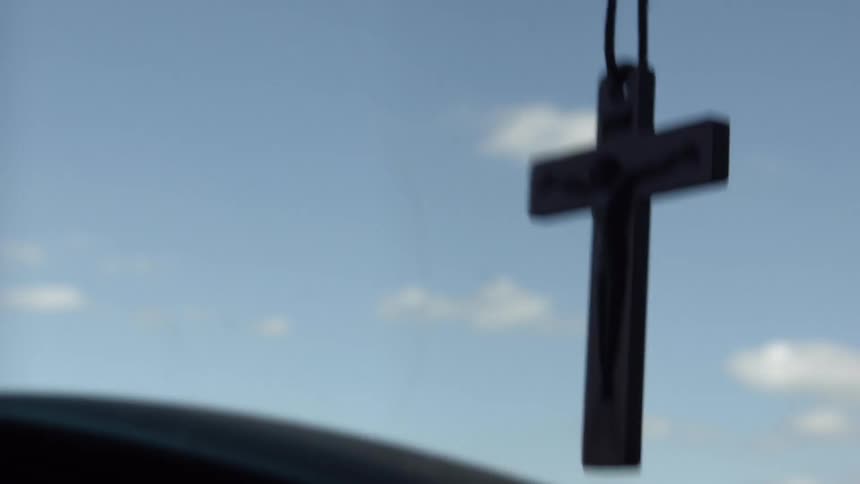 A cross dangling from a rear view mirror