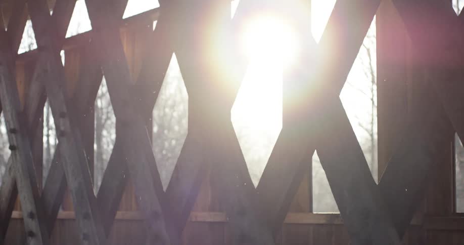 The sun peeking through a wooden fence lattice