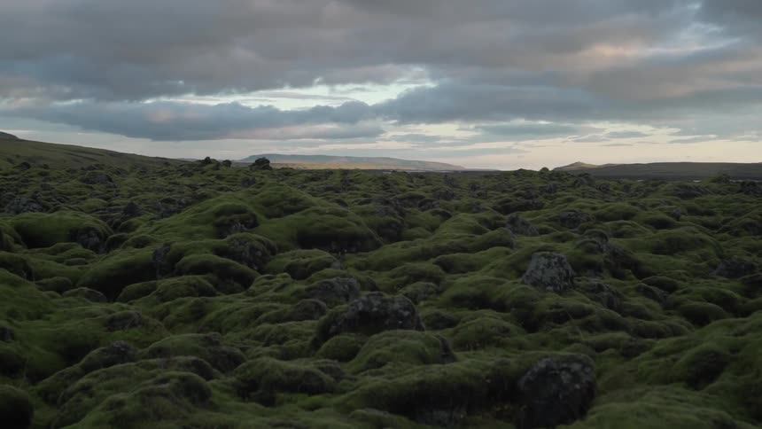 Grassy hills stretch into the distance with clouds floating overhead