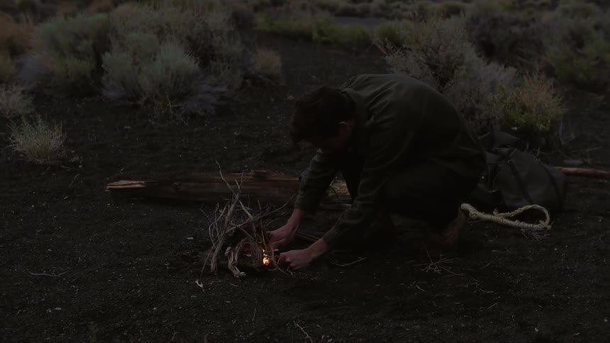 Man trying to start a fire outside on a cloudy night