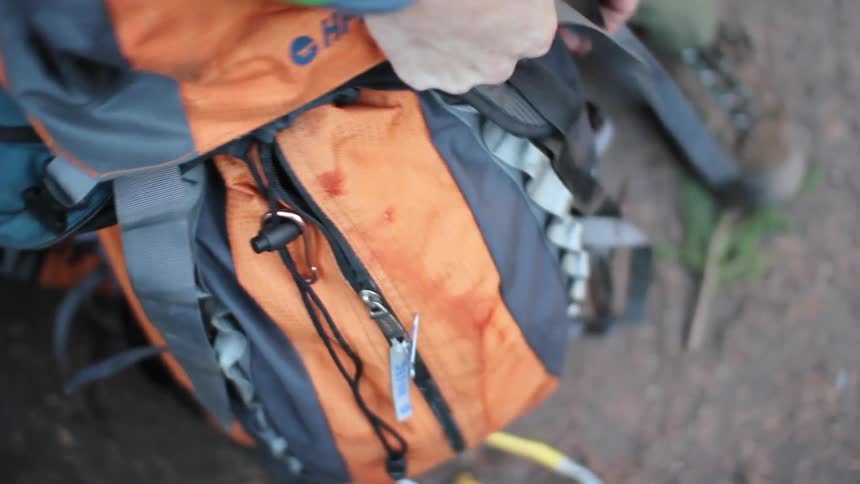 A man closing a backpack and adjusting the straps