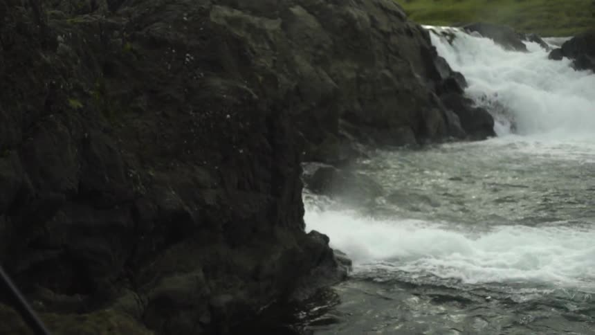 A blonde woman photographing cascading rapids on a mountainside