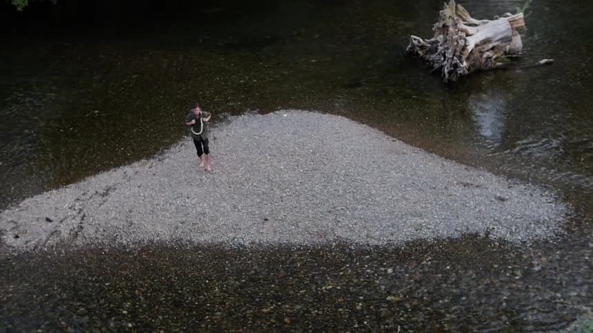 A hiker wades through a shallow river