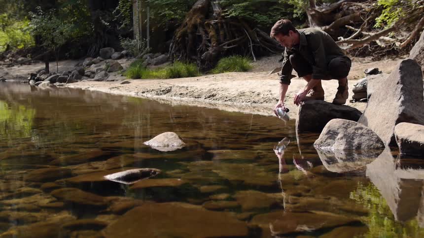 A man filling a canteen from the creek