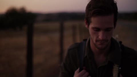 A man with a backpack walks near a fence,