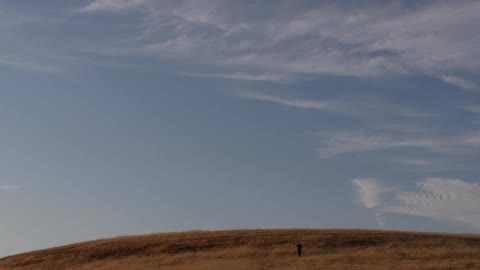 A person traversing a grassy foothill