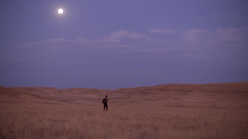 Man walking through valley in sunlight