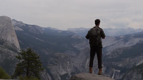 A man with a backpack overlooks a mountain range