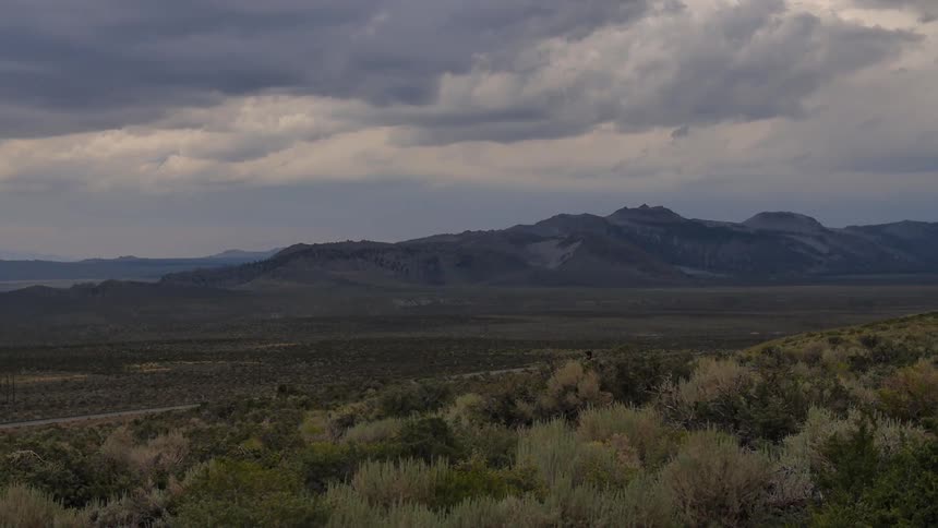 A man hikes through a valley with mountains in the background