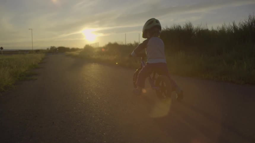 A young child bicycles down a path