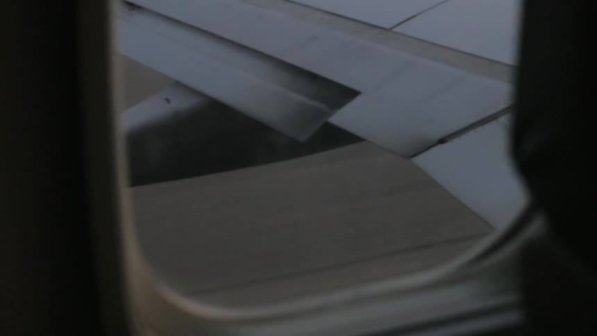 Someone is looking out the window of an airplane that is taxiing down the runway