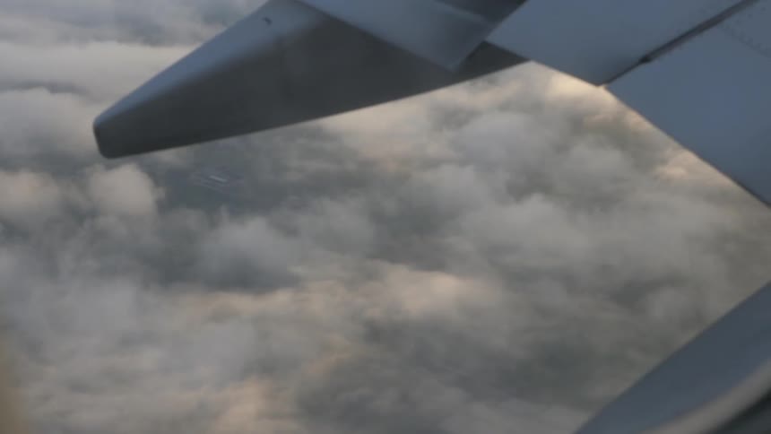 A plane flies high over the clouds