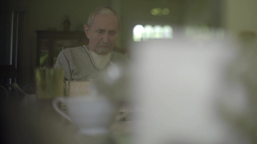 A sad, old man drinking coffee alone