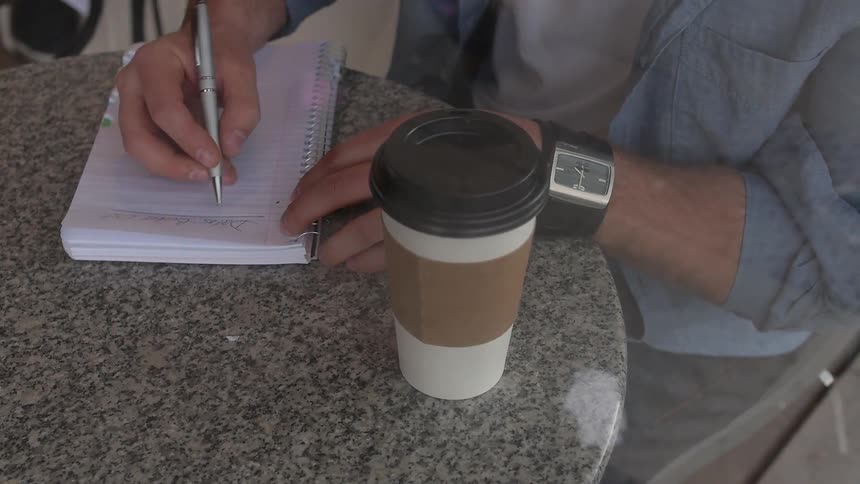 Man sitting at the table writes down in the cafe