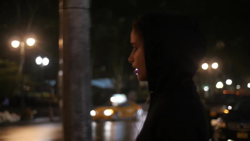 A woman is walking through a street at night